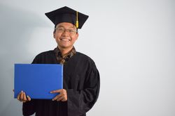 Proud male graduate in studio shoot holding certificate
