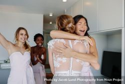 Bridesmaids hugging the bride and smiling 4OeLg0