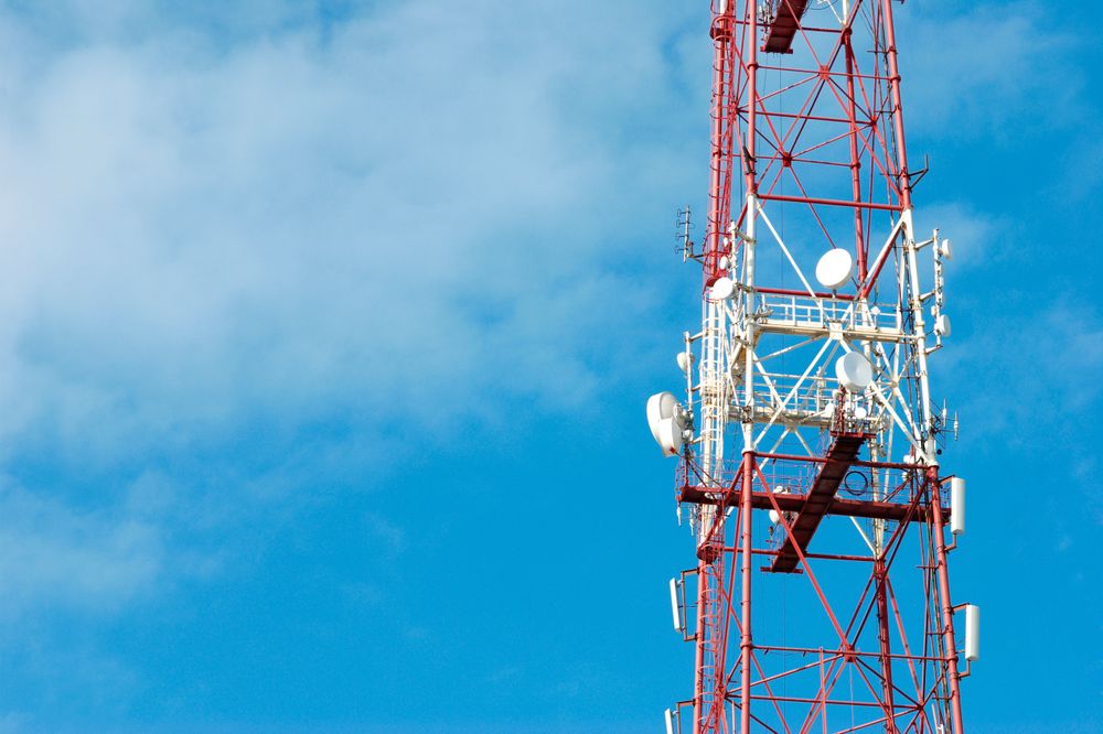 Red Striped Telecommunications Tower Against a Clear Blue Sky
