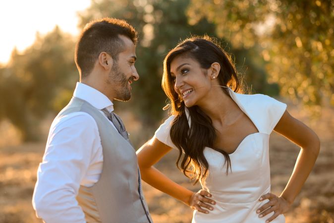 Bride with hands on hip looking at husband