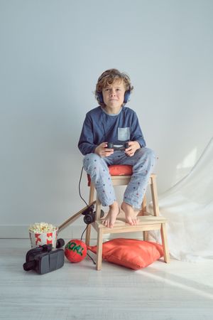 Concentrated preteen boy in headphones playing video game with j