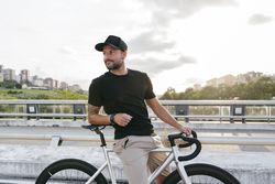 Cheerful man with bicycle standing on footbridge