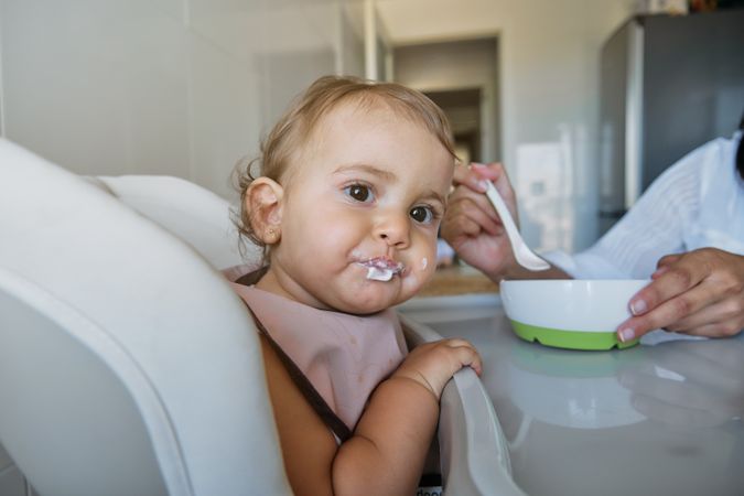 Mother feeding little daughter in kitchen