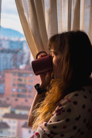 Woman enjoying hot beverage near fridge