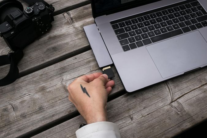 Male tattooed hands with camera and laptop