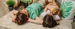 Banner of serene boy and little girl embracing stuffed dog resting surrounded by cushions and plants