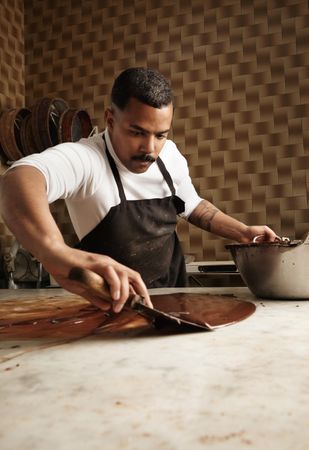 Professional Black male chocolatier working with melted chocolate