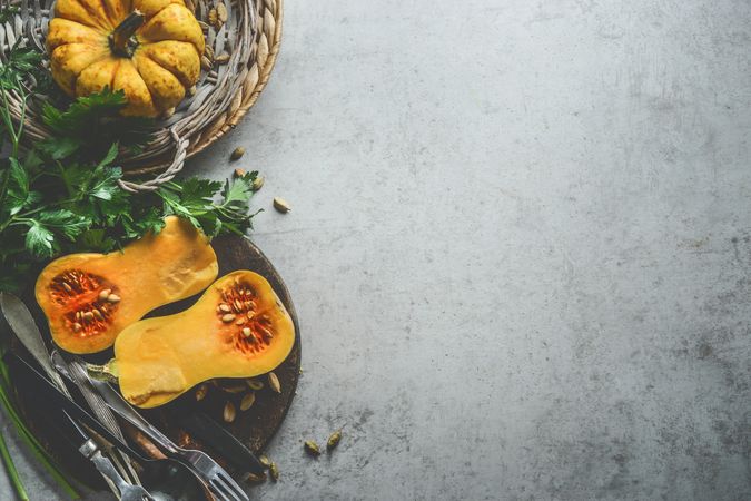 Healthy seasonal food background with pumpkins, fresh herbs and cutlery  on rustic background, top view. Border