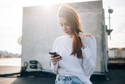 Red haired woman looking at her smart phone on roof