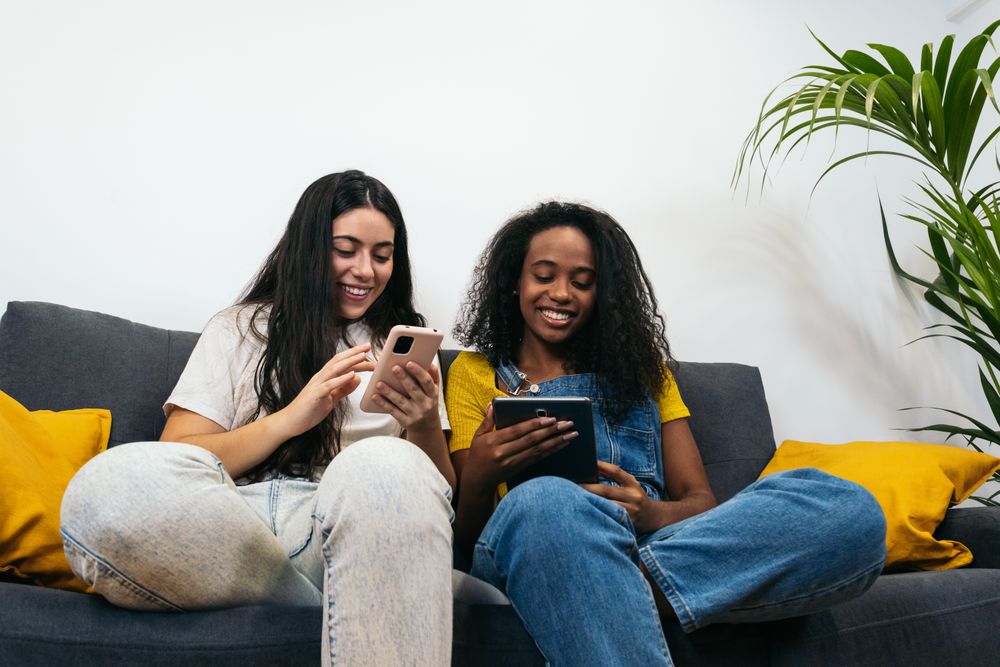 Young women smiling and using digital devices at home