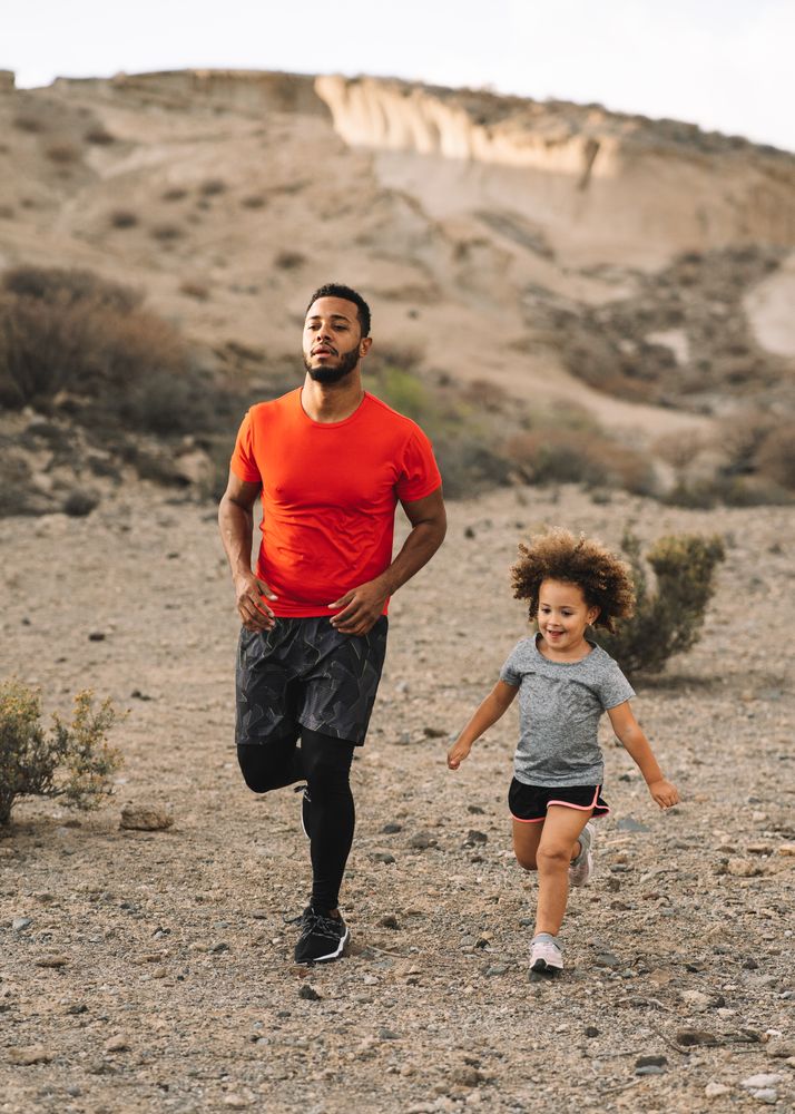 Black man jogging with toddler on nature