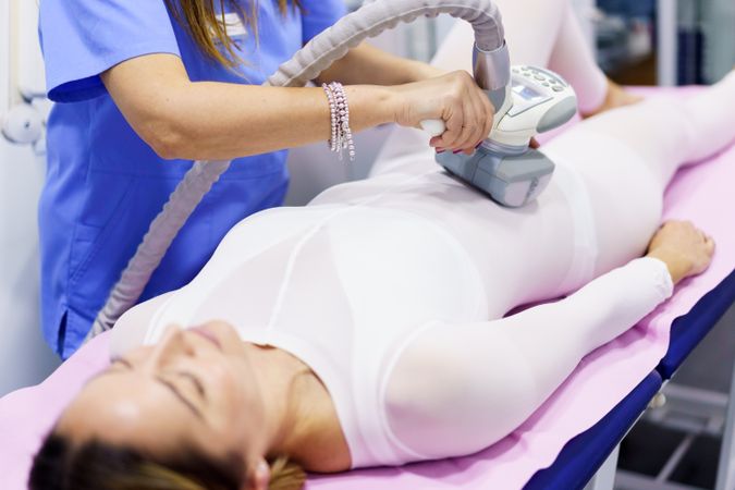 Female lying back in medical spa having a body treatment for fat loss