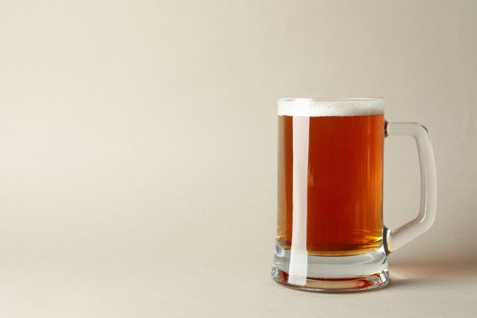 Glass of beer on gray background, space for text