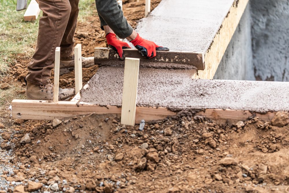 Construction Worker Leveling Wet Cement Into Wood Framing