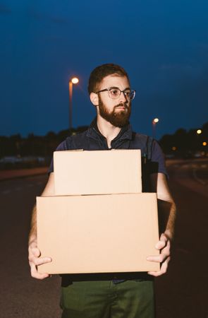 Courier delivering cardboard boxes in evening