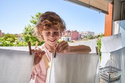 Cheerful preteen boy arranging laundry on clothesline