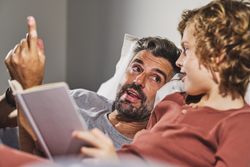 Father and son reading in bed