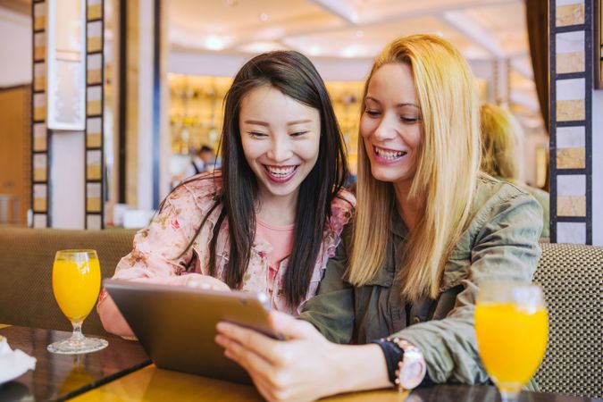Female friends using tablet in cafe