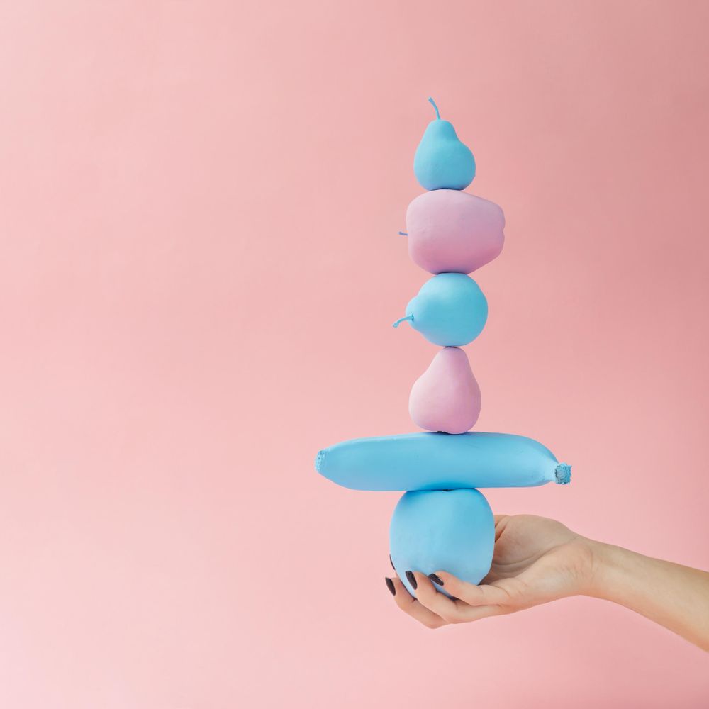 Hand holding pastel painted pink and blue fruits