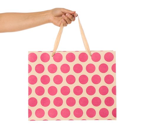 Female hand hold color paper bag isolated on blank background