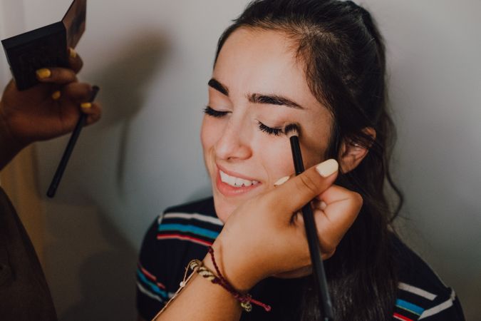 Young woman getting makeup by makeup artist in salon
