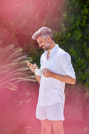 Adult man browsing smartphone in courtyard