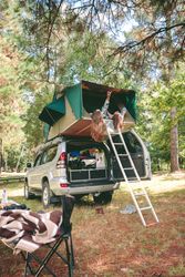 Women resting lying in tent over 4x4 and looking at nature