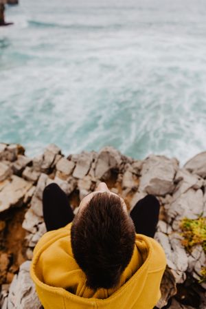 Person in yellow hoodie on stony shore