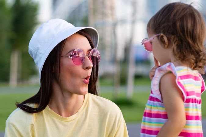 Toddler girl and mom making faces in park