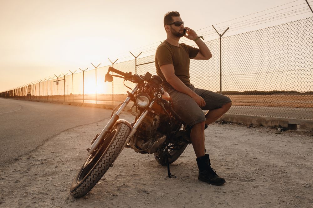 Man sitting on motorcycle and surfing mobile