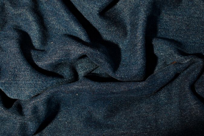 Close up detail crumpled wavy Navy blue jeans fabric background texture.
