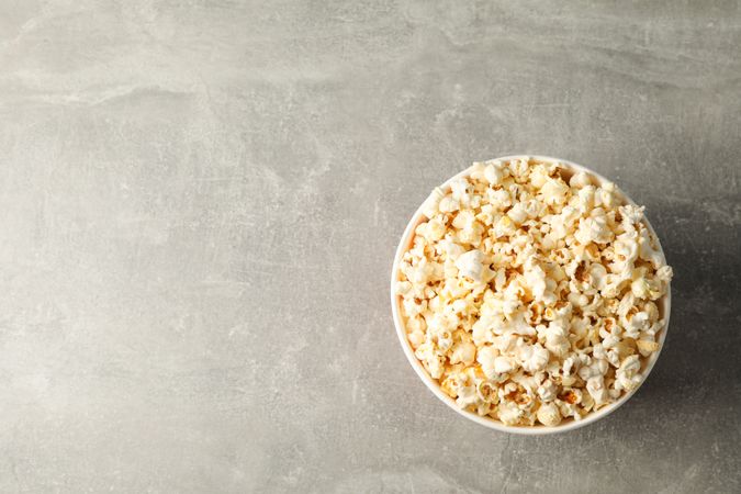 Bucket with popcorn on grey background, space for text
