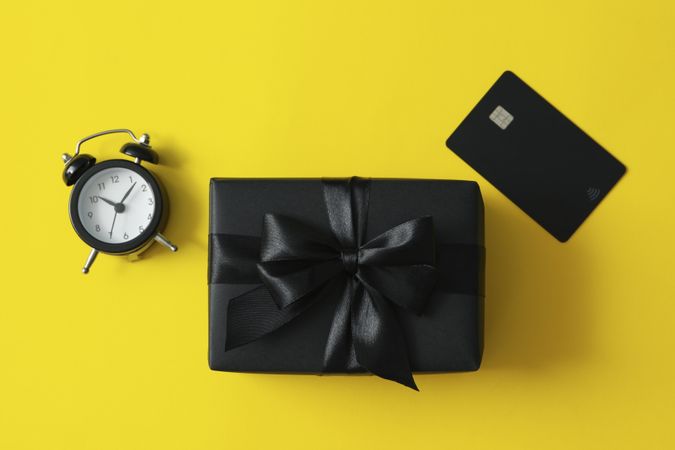 Gift box, alarm clock and card on yellow background