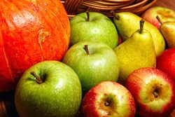 Seasonal fruit and squash on wooden table with wicker basket