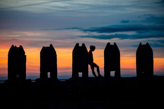 Silhouette of person between stone sculptures in sunset