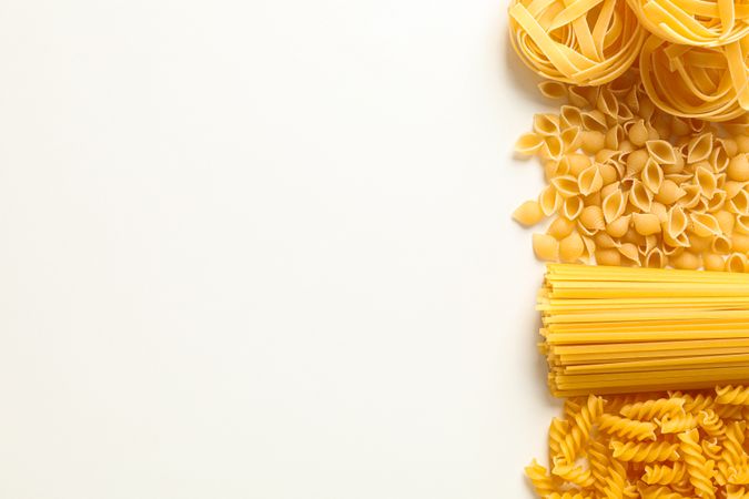 Different pasta on studio background, space for text. Dry uncooked whole pasta