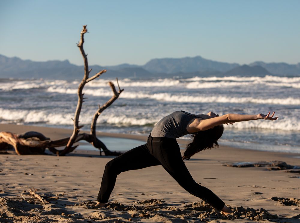 Young woman dancing and posing near water on shore
