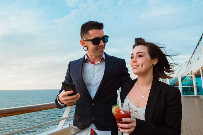 Couple on mobile phone and drink on deck of ship