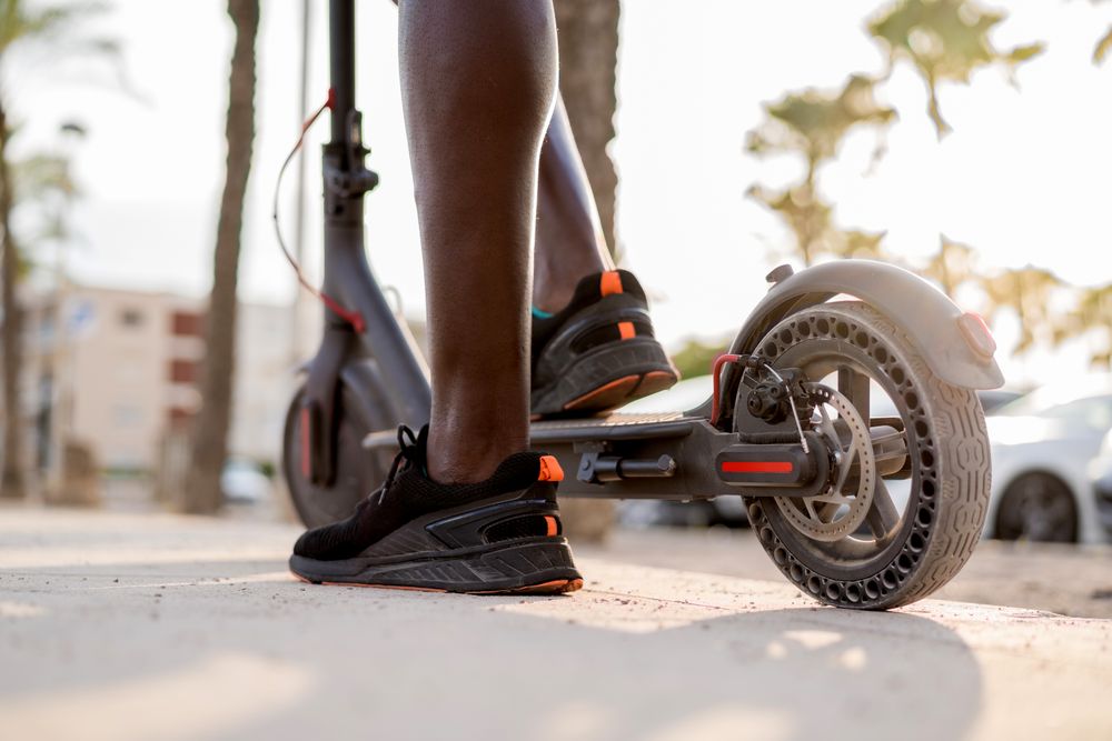 Black man riding scooter in street