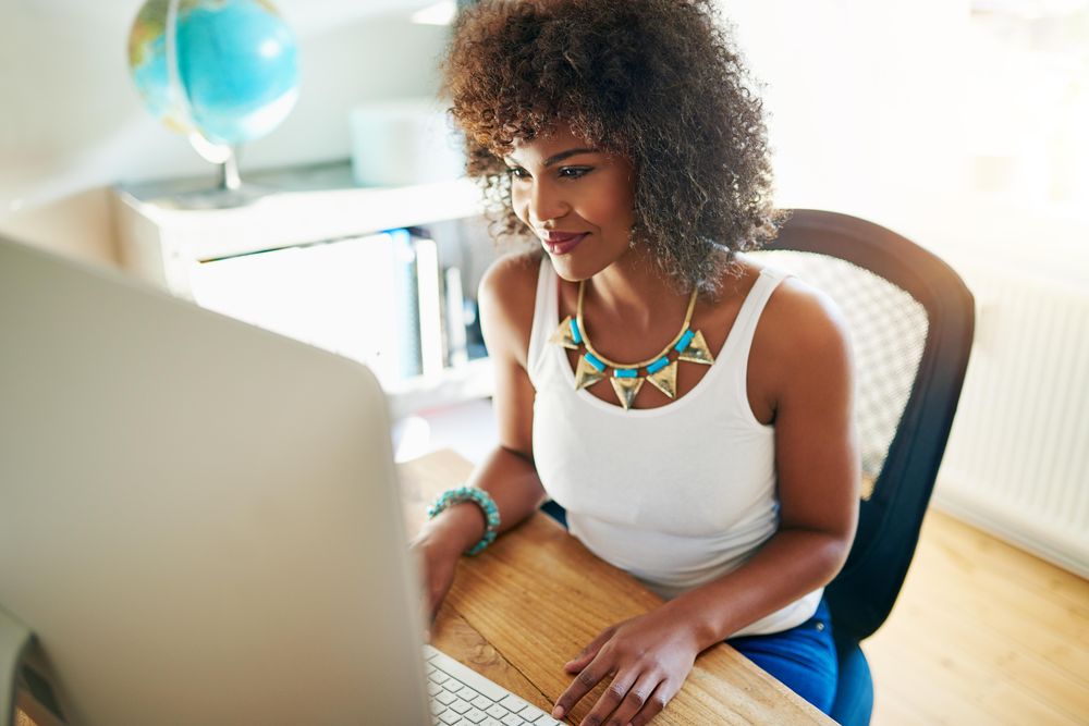 Black female with curly hair working on computer at home