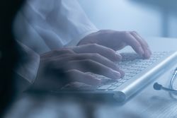 Doctor working at computer keyboard through X-ray film