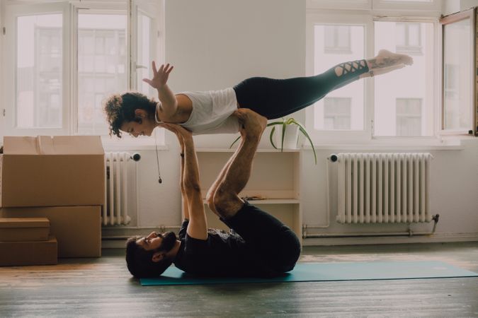 Hipster couple practicing yoga together at home