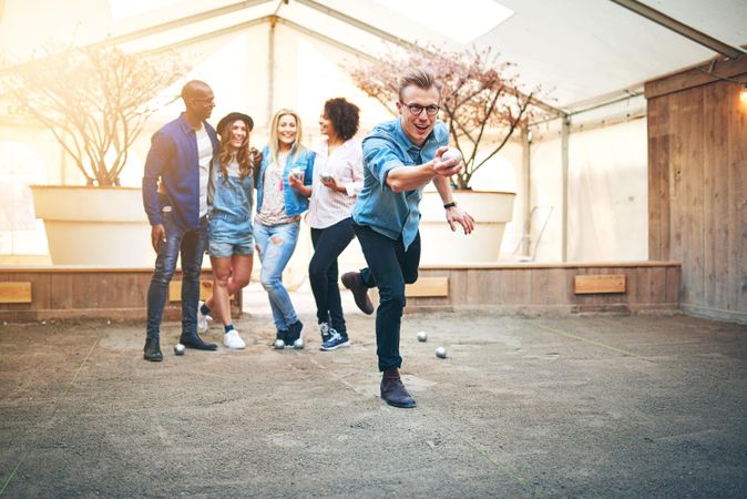 Multi-ethnic group of friends playing pétanque outside