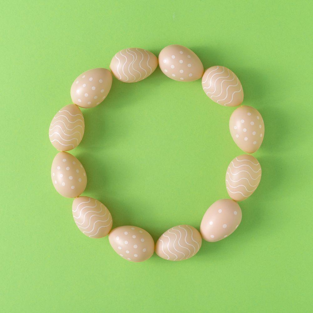 Wreath of Easter brown eggs on pastel green background