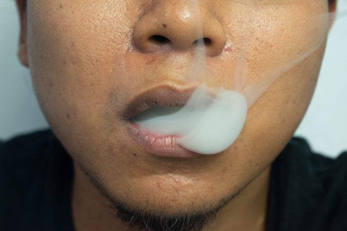 Face of man exhaling cigarette smoke