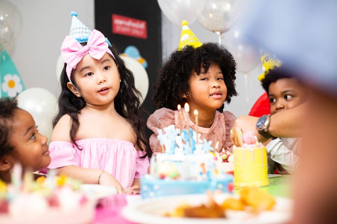 Diverse group of children at a birthday party with cake, balloons and candles