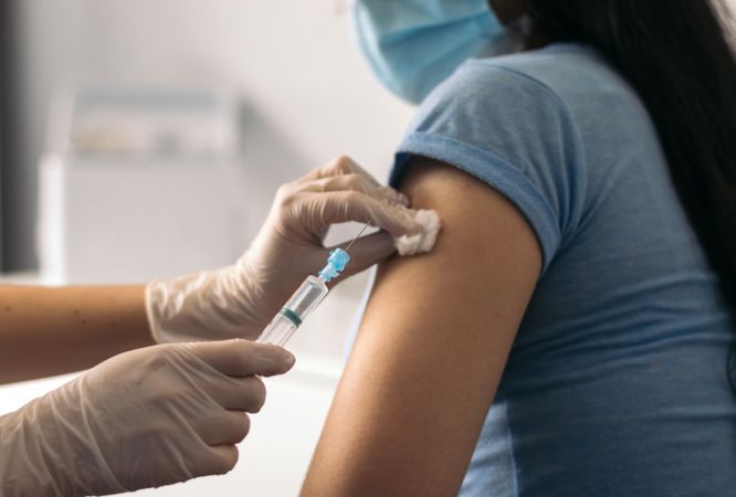 nurse putting a vaccine on patient with mask