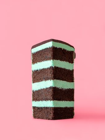 Slice of mint layered cake isolated on a pink background