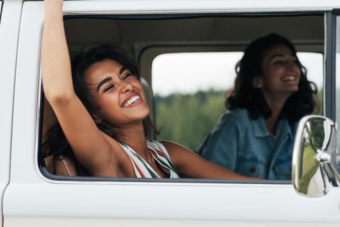 Two girlfriends laughing in a van