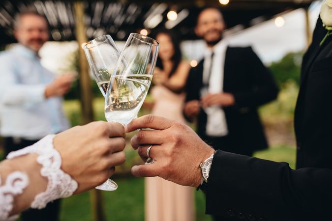 Close up of new married couple toasting champagne glasses at wedding party
